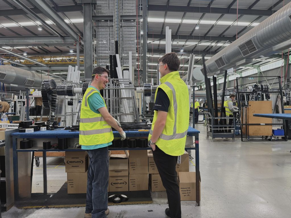 Two workers in conversation at a workbench in a fabrication plant
